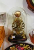 A brass skeleton clock under glass dome