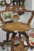 An oak revolving desk chair with cane seat