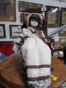 A porcelain collector's doll on rocking chair