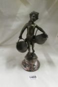 A bronze figure of a child carrying baskets