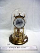 A Kundo brass anniversary clock under glass dome
