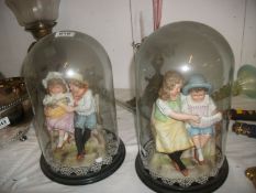 A pair of Victorian porcelain figure groups under glass domes