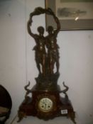 A French marble and spelter clock with enamelled dial and surmounted with figure