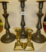 A set of 3 early 20th century pewter candlesticks and a pair of Georgian brass candlesticks