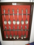 A set of 12 Dicken's character pewter spoons on rack