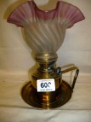 A brass hand oil lamp with frosted pink edged shade