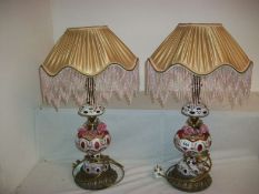 A pair of overlaid cranberry glass table lamps with shaded