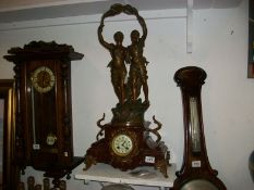 An ornate French mantel clock surmounted pair of figures and with enamel dial