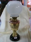 A Victorian oil lamp in copper and brass with white globe shade