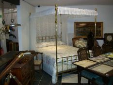 A brass four poster bed complete with mattress, drapes and quilt