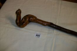 A rustic walking stick with carved snake handle