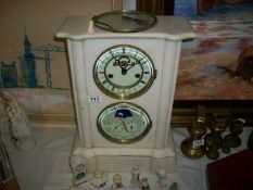 A white marble clock with visible escapement and day, date, month moon phase sweep hand