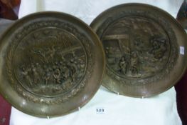 A pair of brass plaques being Roman scenes in relief