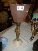 A brass figurine table lamp with pink glass shade