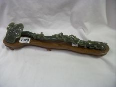 A carved jade branch on wooden base