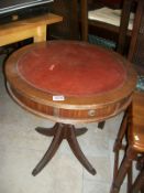 A mahogany drum table with red leather top