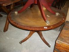 A circular mahogany table with leather inset top and brass lion paw feet