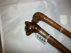 A walking stick with cat head handle and a walking stick with dog head handle