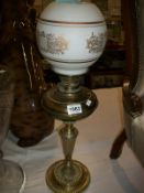 A brass oil lamp with frosted glass shade