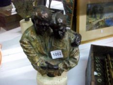A bronze effect bust of an old woman and an old man on stone base