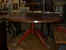 An oval mahogany coffee table with brass lion paw feet