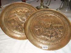 A pair of metal plaques with Grecian scenes in relief (29cm diameter)