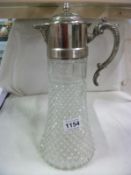 A glass lemonade jug with ice compartment and plated top