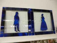 A pair of leaded and stained glass panels being silhouetted of a lady and gentleman