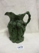 A Green pottery jug with grotesque style figure on each side