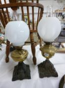 2 Victorian oil lamps on cast bases with brass fonts and white globe shades