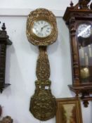 An ornate brass wall clock with 2 weights and embosses pendelum