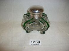 A glass inkwell with silver top