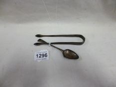 A silver spoon and silver sugar tongs