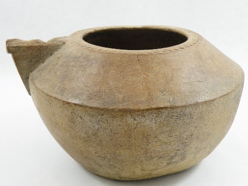 Tribal art: A carved hollowed wooden pouring vessel with worn spout, raised decoration to rim 30cm