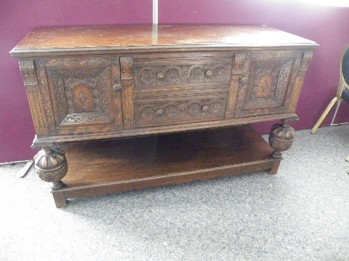 An early 20th century carved oak sideboard buffer of Jacobethan design, the rectangular top with