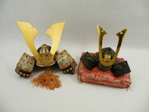 Two late 20th C Japanese Samurai helmets, one of cast metal and bronze on  a reg gilt cushion