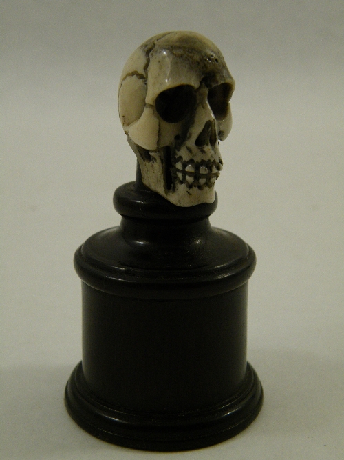 Memento Mori : a carved bone human skull supported on a turned rosewood pedestal 8cm tall