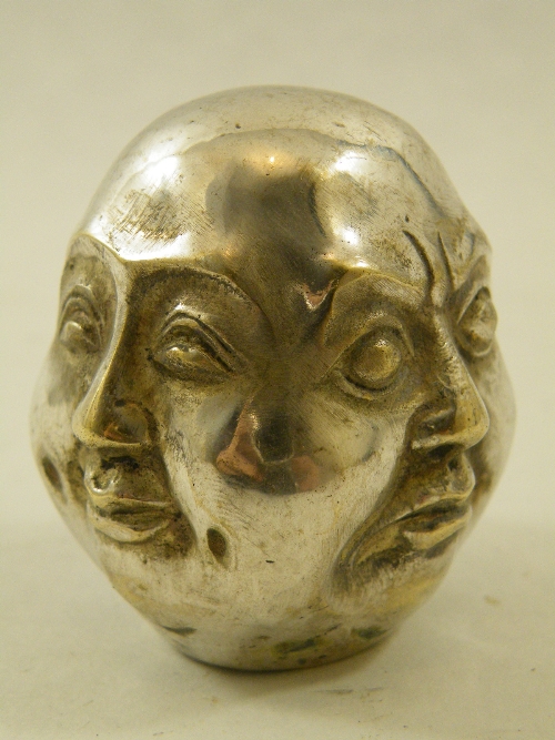 A white metal paperweight displaying the four faces of Buddha, cast seal mark to base. 6cm high