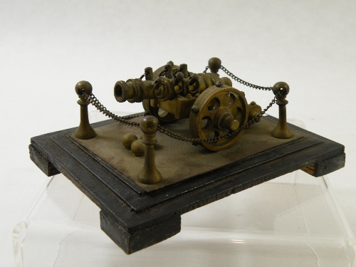 A miniature bronze or brass desk model of an 18th Century cannon with chain and pillars on stepped