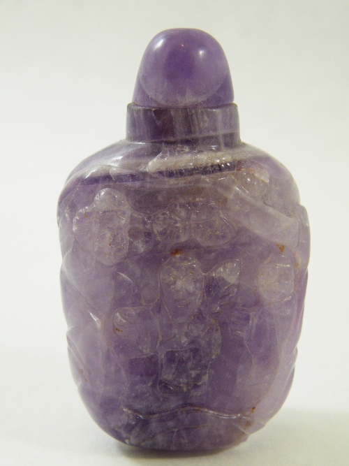 A Chinese amethyst snuff bottle and matching stopper intricately carved to the front with a figure