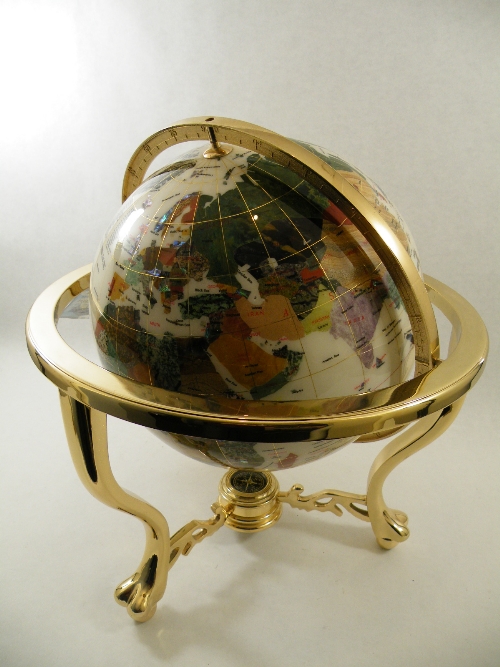 A large gemstone set globe of the World mounted on a gold plated brass surround with compass under