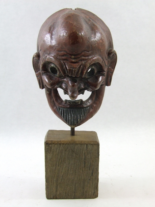 A 19th C carved and painted Balinese theatre mask mounted on a later wood and iron stand 35cm high