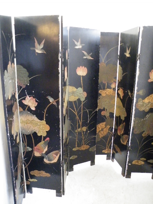 A pair of four panel Oriental black lacquer screens decorated with birds and foliage - each panel