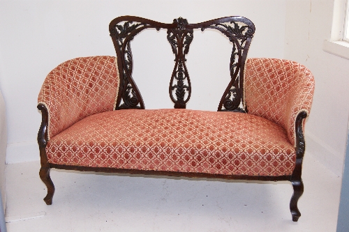 A large late Victorian mahogany  two seater salon sofa with elaborately carved back rest and