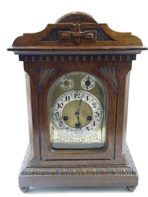 An early 20th C oak cased German mantle clock of bracket type case with Art Nouveau engraved brass