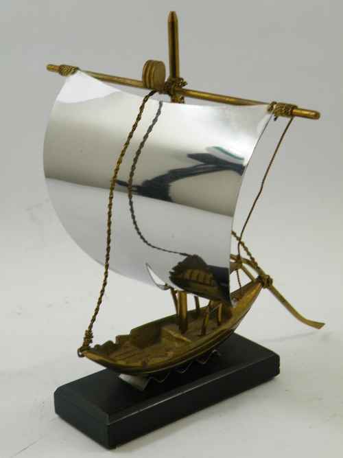 A brass desk top model of an Asian sailing boat with polished steel sail 20cm high