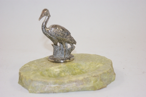 A silvered metal figure of a heron supported in a marble pin try 12cm wide