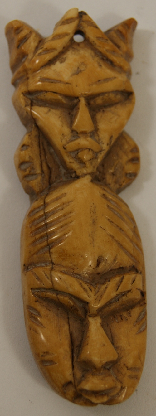 An African, possibly Nigerian ox bone token or pendent of two carved faces 9cm high