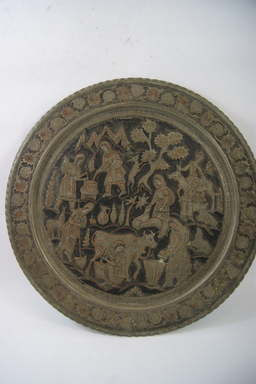 A Middle Eastern copper and beaten metal wall charger depicting a rural scene 50cm diameter