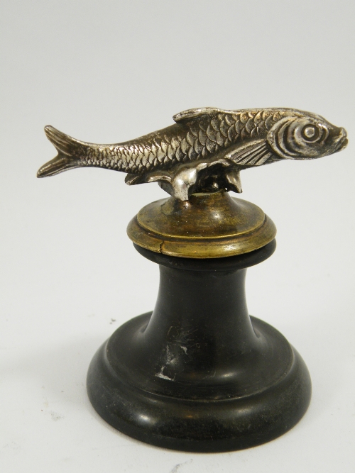 A small turned slate desk weight topped with a white metal fish - possibly a trout. 7cm high